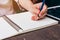 Asian woman hand writing pencil on notebook in coffee shop with