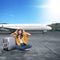 Asian woman with a hat and suitcase sitting with an unhappy expression on the runway