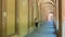 Asian woman in hat, tshirt and sneakers leaning against wall of portico