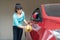 Asian woman having happy in home washing owner red car with soapsuds and sponge during Staying at home using free time about their