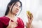 Asian woman having heartburn, acid reflux after eating burger, eating junk food concept
