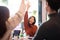 Asian woman and her team hand raised for happy winning success in coffee shop with team.