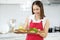 Asian woman hold wooden plate containing fish or meat also look to food and stand in the kitchen with smiling