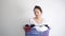 Asian woman holding basket of used clothes for washing. boring face. Concept of housework.