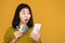 Asian woman holding smart phone and credit card shocked with overspending money from shopping online