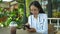 Asian woman  holding smartphone sitting outdoors cafe. Portrait of young woman typing smartphone at coffee break.