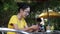 Asian woman holding smartphone sitting outdoors cafe. Portrait of young woman typing smartphone at coffee break.