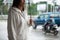 Asian woman holding umbrella while waiting taxi and standing on city sidewalk street in the rainy day