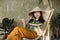 Asian woman holding vegetarian salad while sitting on folding chair with organic vegetables