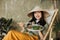 Asian woman holding vegetarian salad while sitting on folding chair with organic vegetables