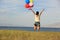 asian woman jumping on sunset grassland with colored balloons