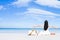 Asian woman, long black hair, wore white dress and hat sitting on the beach near the woven bags and sunglasses and facing back by