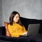 Asian woman looking at laptop, working at home, liying on sofa. Unhappy, upset Japanese female