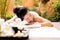 Asian woman lying down on massage bed with scrub sugar and salt aroma at outdoor natural.  wellness center, so relax and lifestyle