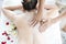 Asian woman massaging spa with salt. Beauty therapist pouring salt scrub on woman back at health spa
