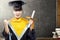 Asian woman in mortarboard hat and diploma graduating from college in the classroom with piles of books and blackboard background