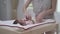 Asian woman Mother changing baby`s diaper on table at home. happy infant comfortable when cleaning. mom playing with kid.