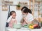 Asian woman mother and daughter play together in kitchen,mom hold tablet for teach little girl how to cook in semester break,