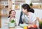 Asian woman mother and daughter play together in kitchen,mom hold tablet for teach little girl how to cook in semester break,