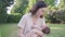 Asian woman mother holding sleeping baby infant on mat outdoor picnic in green garden. mom touching kid head and hair with love. n