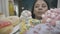 An Asian woman opens the doors of a refrigerator filled with desserts close up. A woman greedily examines desserts