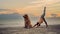 Asian woman performs yoga stretching exercises with dog at the beach. Golden Retriever lifestyle on summer