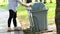 Asian woman picking up litter from the floor into the trash can,female people picking up garbage plastic bag on the grass at park,