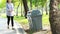 Asian woman picking up litter from the floor into the trash can,female people picking up garbage plastic bag on the grass at park,