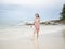 Asian woman in pink dress walking on beautiful beach at Samed, Thailand.