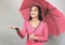 Asian woman in pink  long sleeve t-shir , holding pink umbrella, stretching arm, holds out her palm to catch rain falling water.