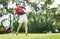 Asian woman playing golf swinging golf club for teeing off in course