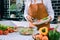 Asian woman is pouring ingredients that are prepared to make a salad into a salad bowl