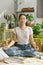 Asian woman practice meditation in lotus position for relieve stress and tension, Woman sitting in living room