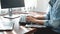 Asian woman programmer looking on keyboard to typing code data about new project on laptop while working