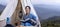 Asian woman reading book while on a solo trekking camp on the top of the mountain with small tent for weekend activities and