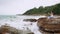 Asian woman on rock cliff near the sea, using mobile smart phone taking photo of the view. wave hitting stone on the beach. freedo