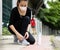 Asian woman runner wearing hygiene protective face mask sitting and tieing shoe rope during workout running in city park. Concept