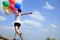 Asian woman running on mountain peak rock with colored balloons