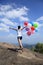 Asian woman running on mountain peak rock with colored balloons