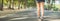 Asian woman`s legs while jogging in the park covered with plenty of trees and warm sunlight.