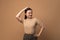 Asian woman scratching her head, standing  on beige background