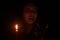 An Asian woman shocking pointing cellphone in front of candle light in the dark night