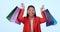 Asian woman, shopping bag and celebration in studio with smile on face for deal by blue background. Japanese girl