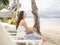 Asian woman sitting on beach chair looking away to sea view. Samed, Thailand.