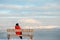 Asian woman sitting on bench on Arctic beach