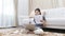 Asian woman sitting in the living room of her home checking company financial documents