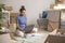 Asian woman sitting in new house using laptop buying decorations online after moving in