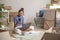 Asian woman sitting in new house using smartphone and laptop buying decorations online after moving in