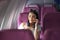 Asian woman sitting on seat in plane cabin near the window and talking on mobile phone.