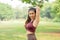 Asian woman with sportswear do arm stretching and also look at camera after exercise in park or garden with morning light